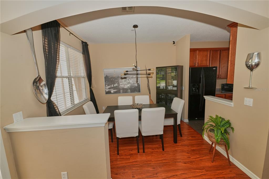 A dining room with a dark wood table, white chairs, and a large wall-mounted spoon — 9135 CARDINAL MEADOW TRAIL, ORLANDO, FL