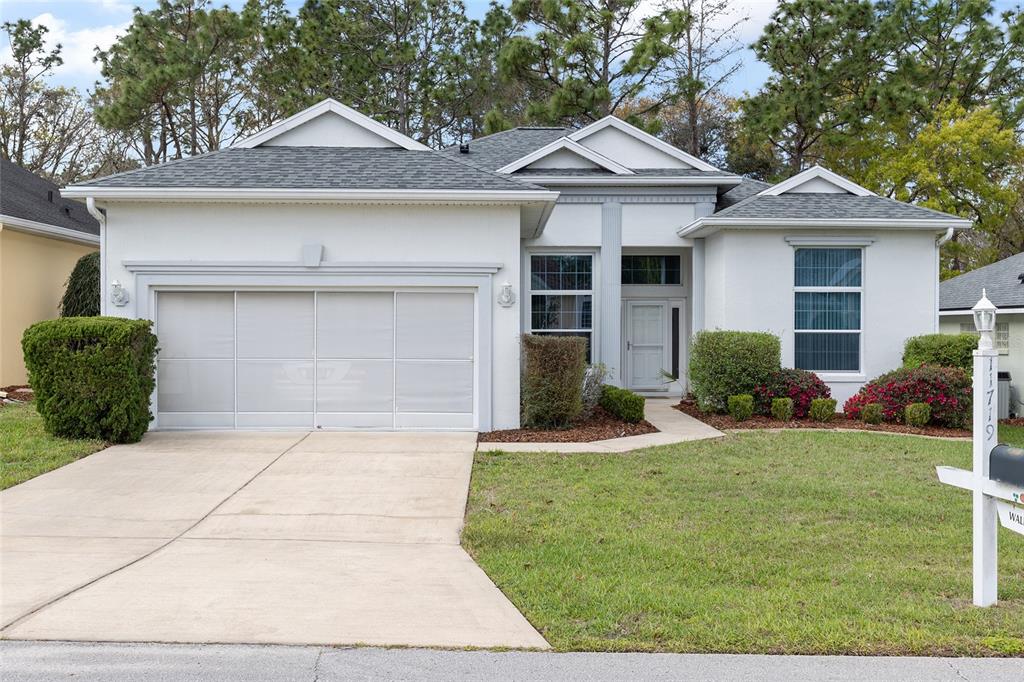 A single-story white house with a two-car garage, a front walkway, and landscaped yard — 11719 SW 72ND CIRCLE, OCALA, FL