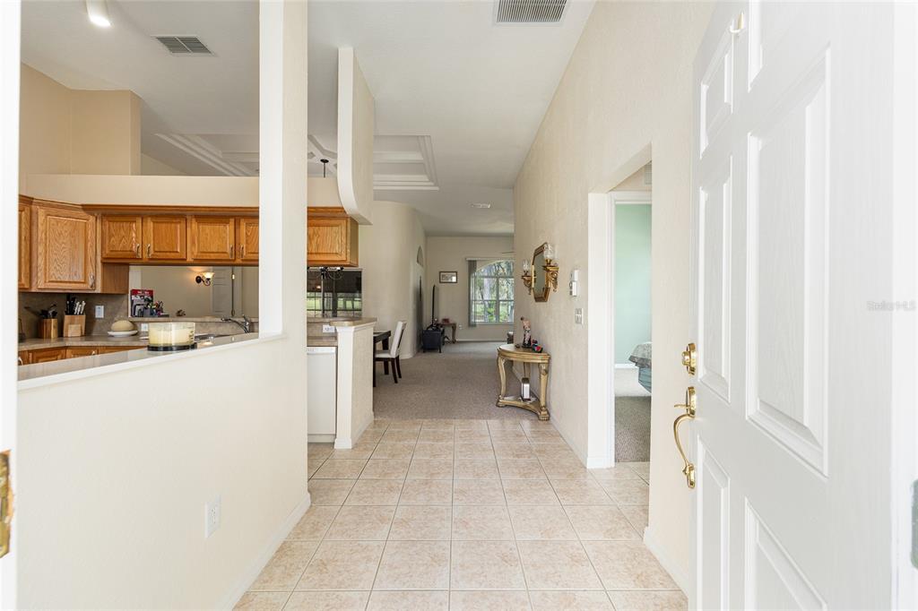 An entryway with tile flooring leads into a carpeted living area and an open kitchen — 11719 SW 72ND CIRCLE, OCALA, FL
