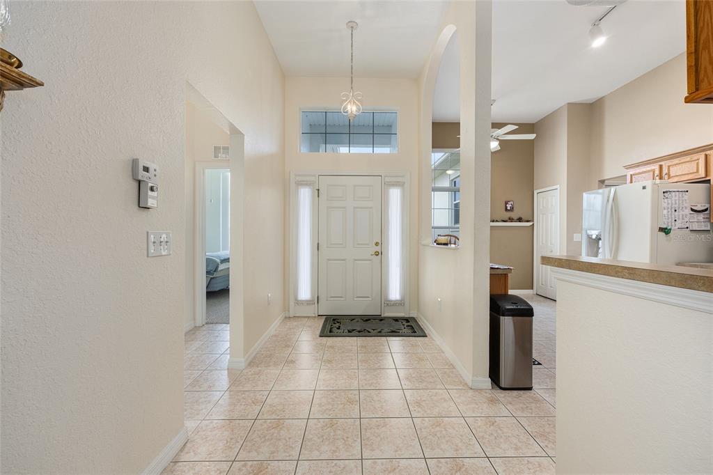 A tiled entryway features a front door with sidelights, a high ceiling, and an adjacent kitchen — 11719 SW 72ND CIRCLE, OCALA, FL