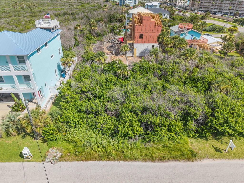 An aerial view shows a vacant, wooded lot situated between two houses near a road — 0 BASS AVENUE, NEW SMYRNA BEACH, FL