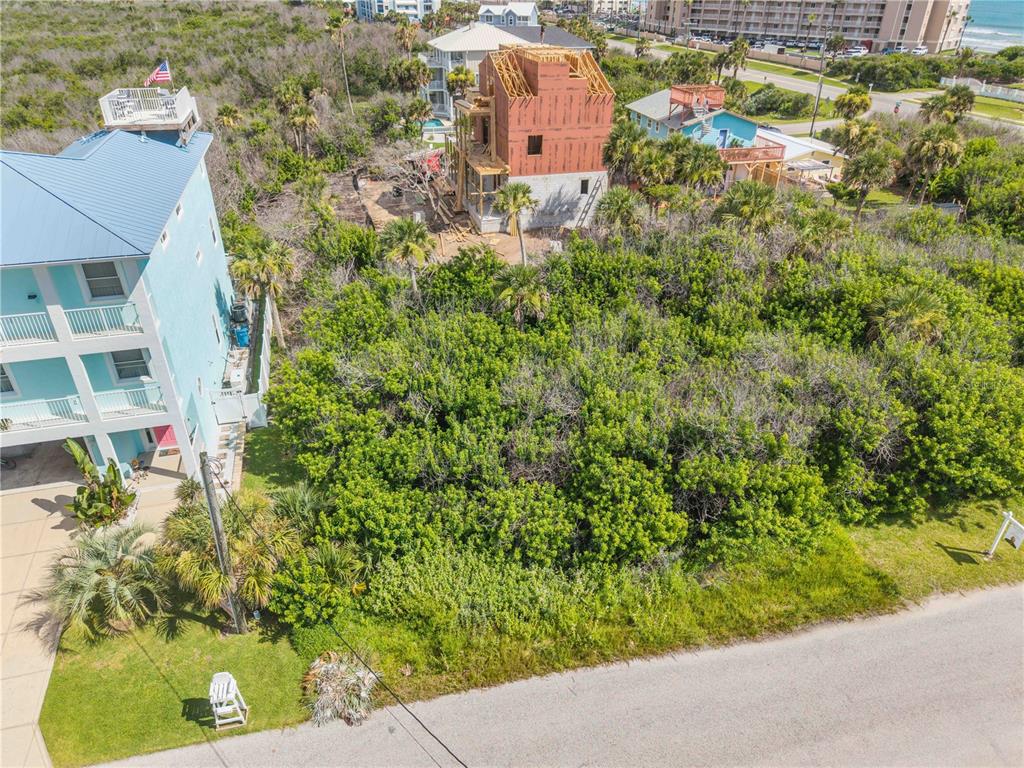 An aerial view shows a vacant, tree-covered lot situated between two houses near the coast — 0 BASS AVENUE, NEW SMYRNA BEACH, FL