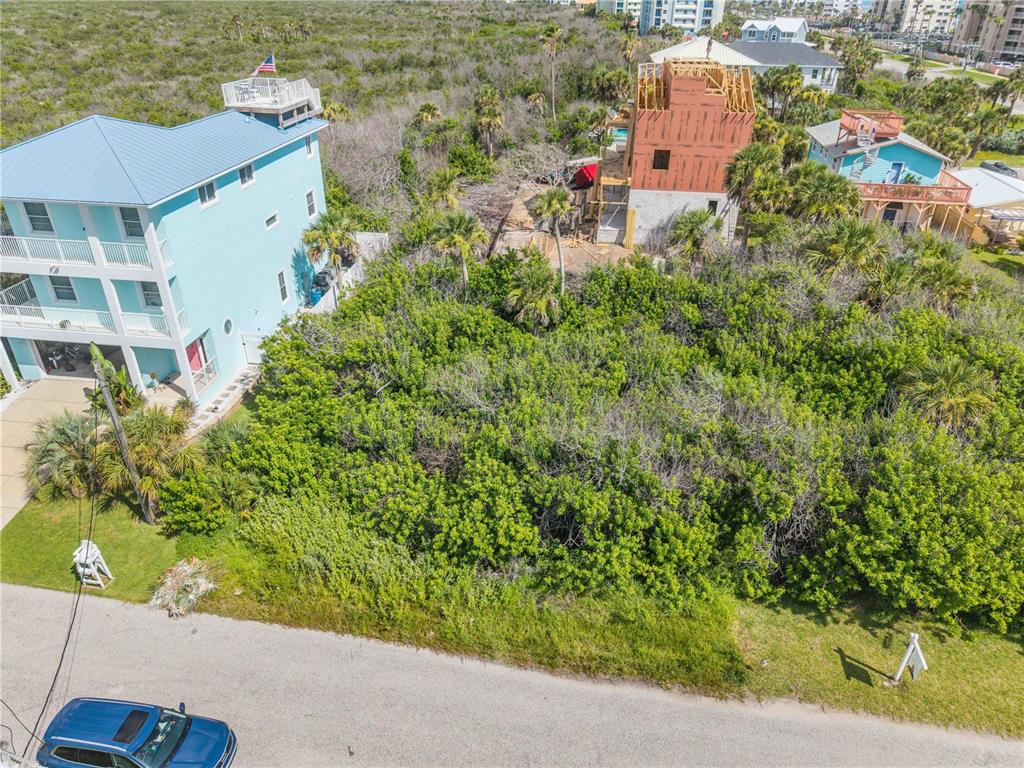 An aerial view shows a vacant, brush-covered lot situated between two houses and a construction site — 0 BASS AVENUE, NEW SMYRNA BEACH, FL