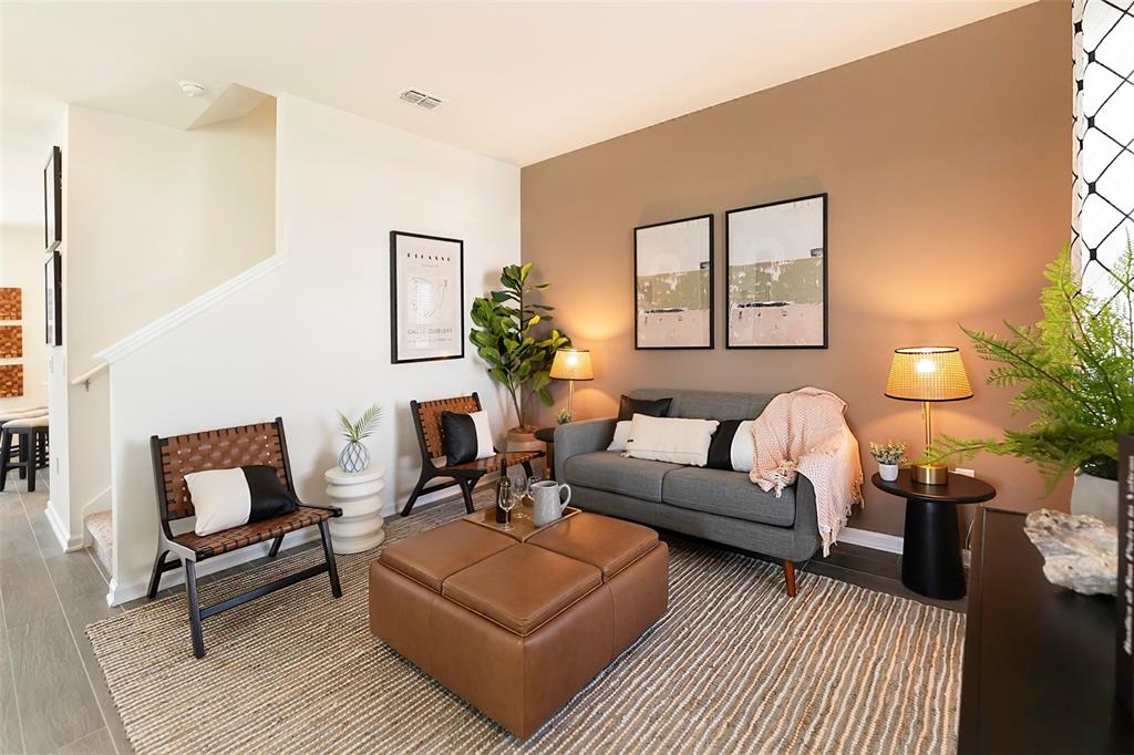 A living room features a gray sofa, two leather chairs, a leather ottoman, and wall art — 6056 PEACEFUL PARK WAY, CLERMONT, FL
