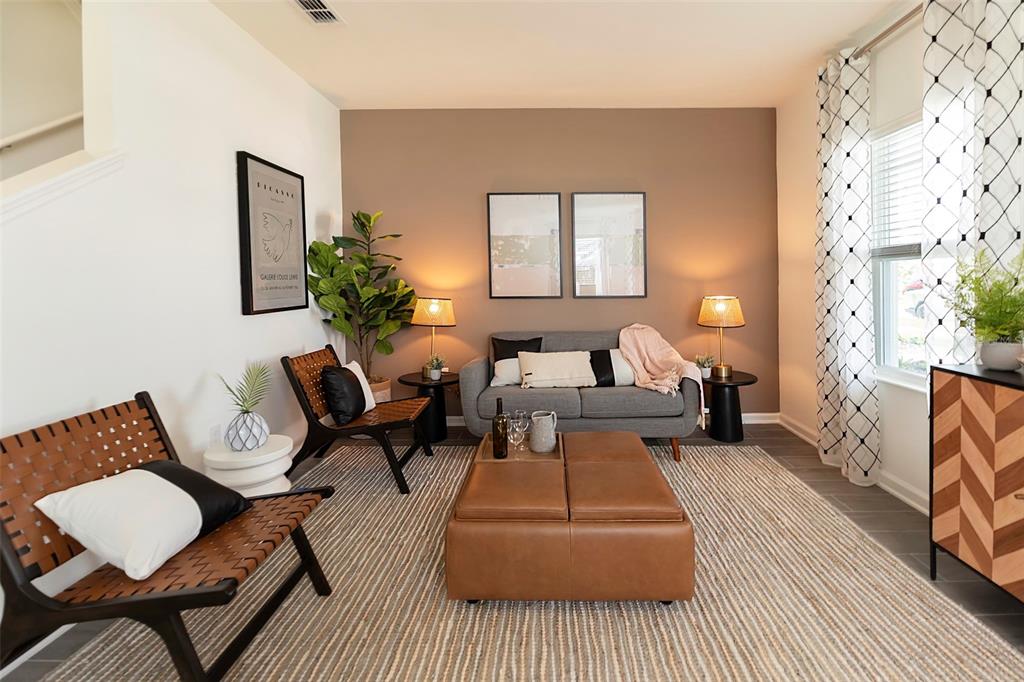 A living room features a grey sofa, leather ottoman, two accent chairs, and a brown wall — 6056 PEACEFUL PARK WAY, CLERMONT, FL