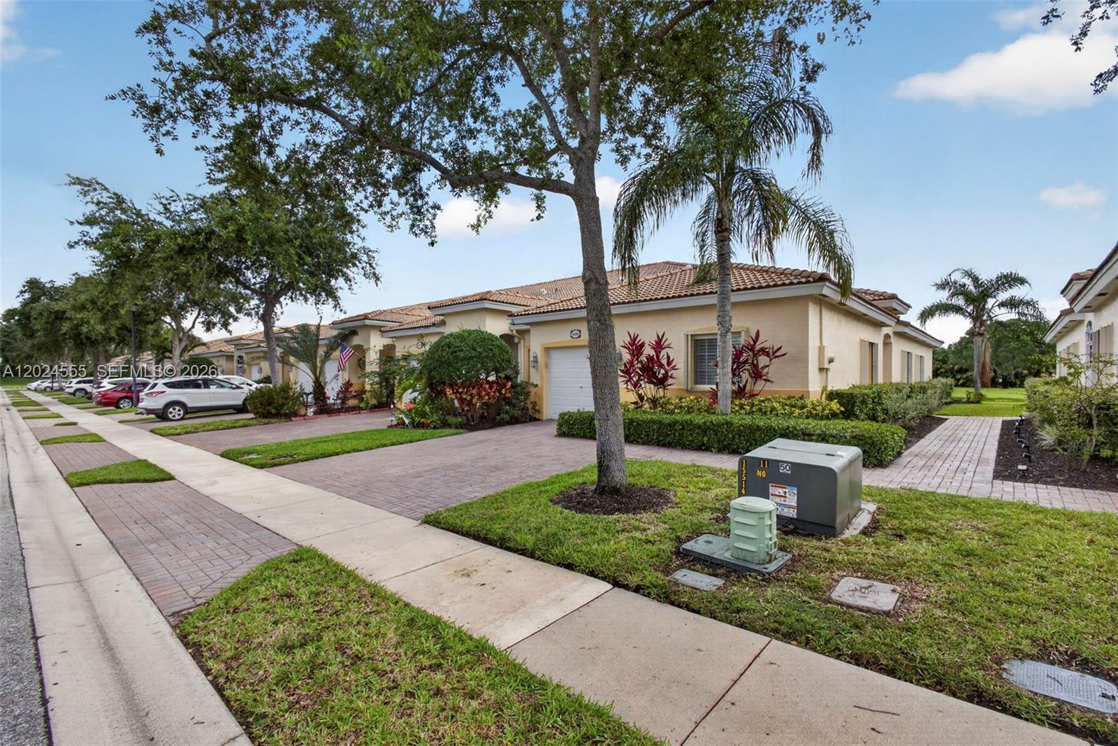 A single-story residential building with a paved driveway, a small lawn, and mature trees — 2368 Windjammer Way, West Palm Beach FL 33411, WEST PALM BEACH, FL