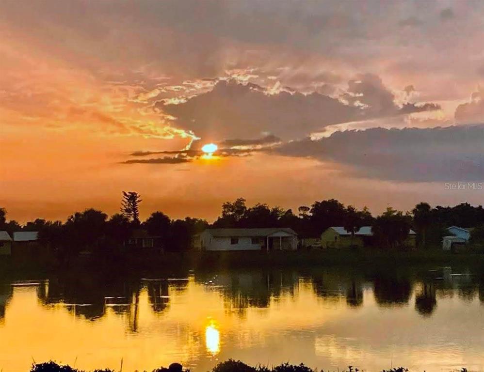 A sunset reflects over a lake in front of several houses and trees — 5081 ADMINISTRATION STREET, PORT CHARLOTTE, FL