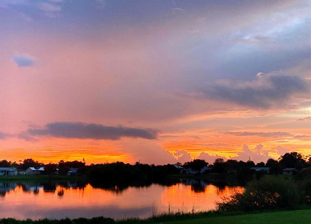 A vibrant sunset reflects over a calm lake with silhouettes of trees and distant houses — 5081 ADMINISTRATION STREET, PORT CHARLOTTE, FL