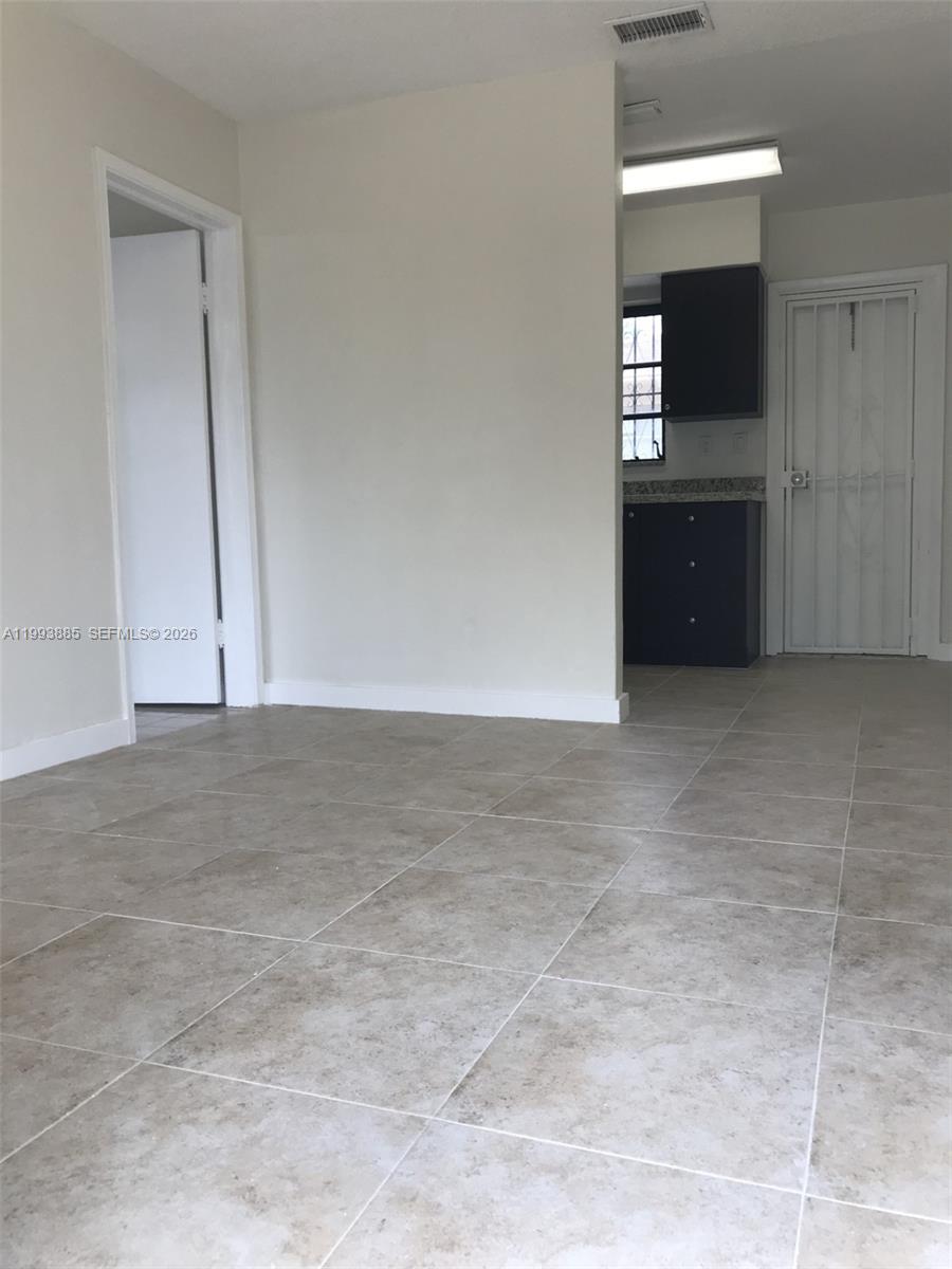 An interior view shows a tiled room with a doorway and an adjacent kitchen area — 2362 NW 34th St # 2, Miami FL 33142, MIAMI, FL