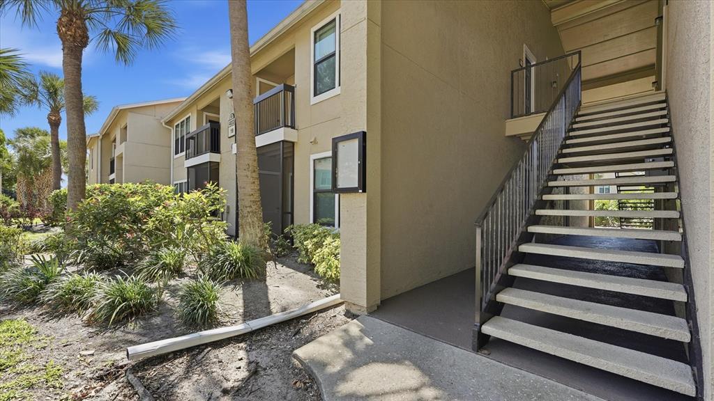 An exterior view of an apartment building with a staircase leading to the upper level — 4033 CROCKERS LAKE BOULEVARD UNIT 28, SARASOTA, FL