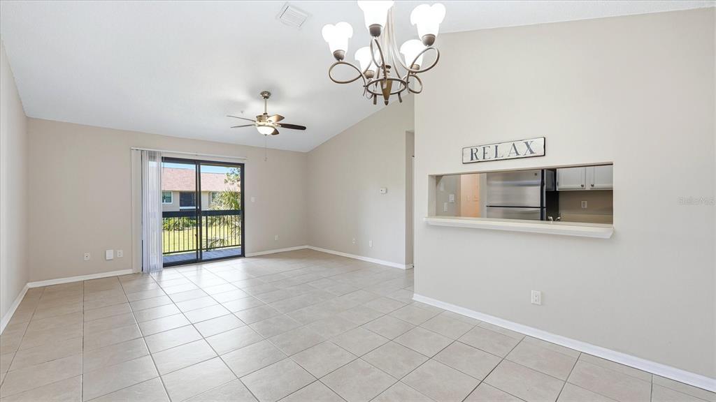 A living room with tile floors, a ceiling fan, a chandelier, and a kitchen pass-through — 4033 CROCKERS LAKE BOULEVARD UNIT 28, SARASOTA, FL