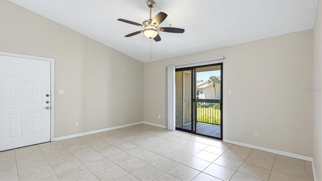 A room with beige tile flooring, a ceiling fan, a white door, and sliding glass doors — 4033 CROCKERS LAKE BOULEVARD UNIT 28, SARASOTA, FL