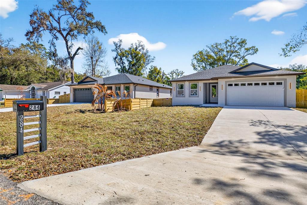 Two single-story houses with driveways and lawns under a blue sky — 284 ROOSEVELT AVENUE, MASARYKTOWN, FL