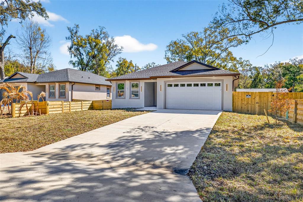 A single-story house with a white garage door, concrete driveway, and wooden fence — 284 ROOSEVELT AVENUE, MASARYKTOWN, FL