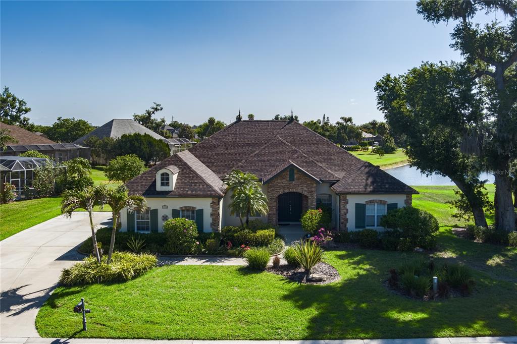A single-story house with a stone facade, dark roof, and green shutters faces a lawn — 3720 59TH AVENUE CIRCLE E, ELLENTON, FL