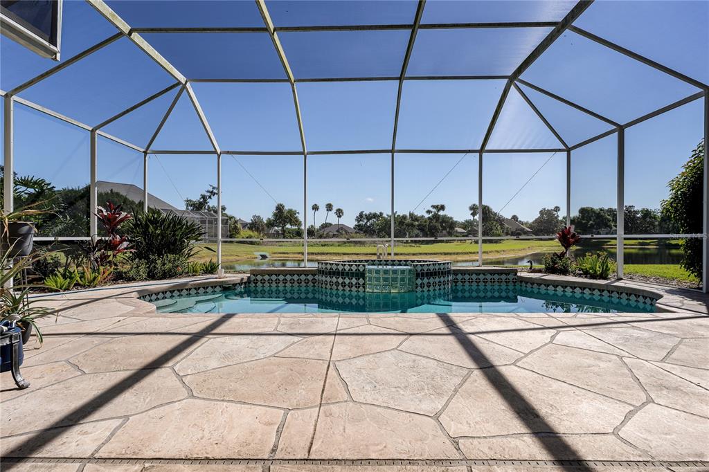 A screened-in patio features a swimming pool with an integrated spa overlooking a pond — 3720 59TH AVENUE CIRCLE E, ELLENTON, FL