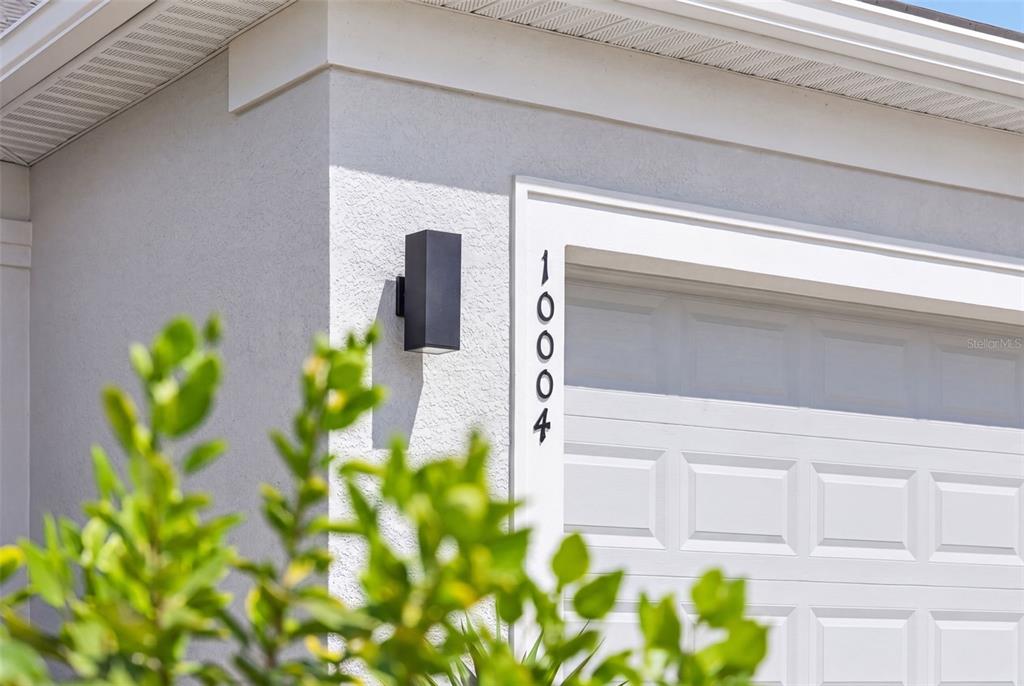 A vertical house number 10004 is mounted on the exterior wall next to a garage — 10004 CORAL SHORE DRIVE, ENGLEWOOD, FL