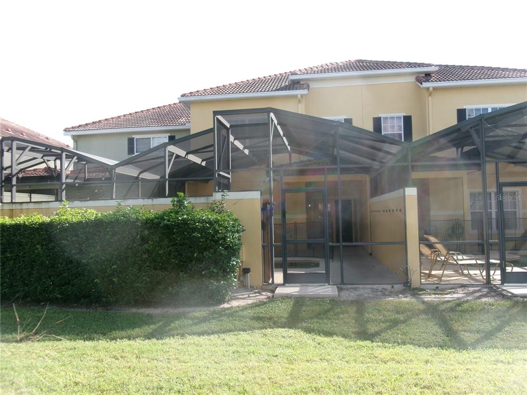 A two-story house features a screened-in patio area with a pool and lounge chairs — 8969 MAJESTY PALM ROAD, KISSIMMEE, FL