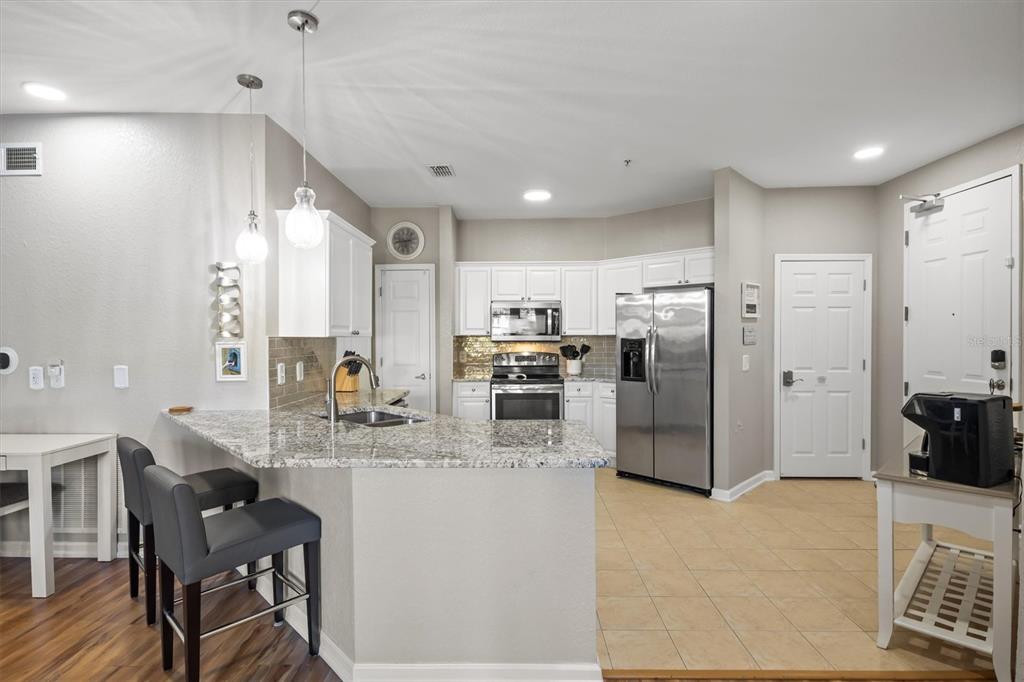 A kitchen features white cabinets, granite countertops, stainless steel appliances, and a breakfast bar — 301 TERRACE RIDGE CIRCLE UNIT 301, DAVENPORT, FL