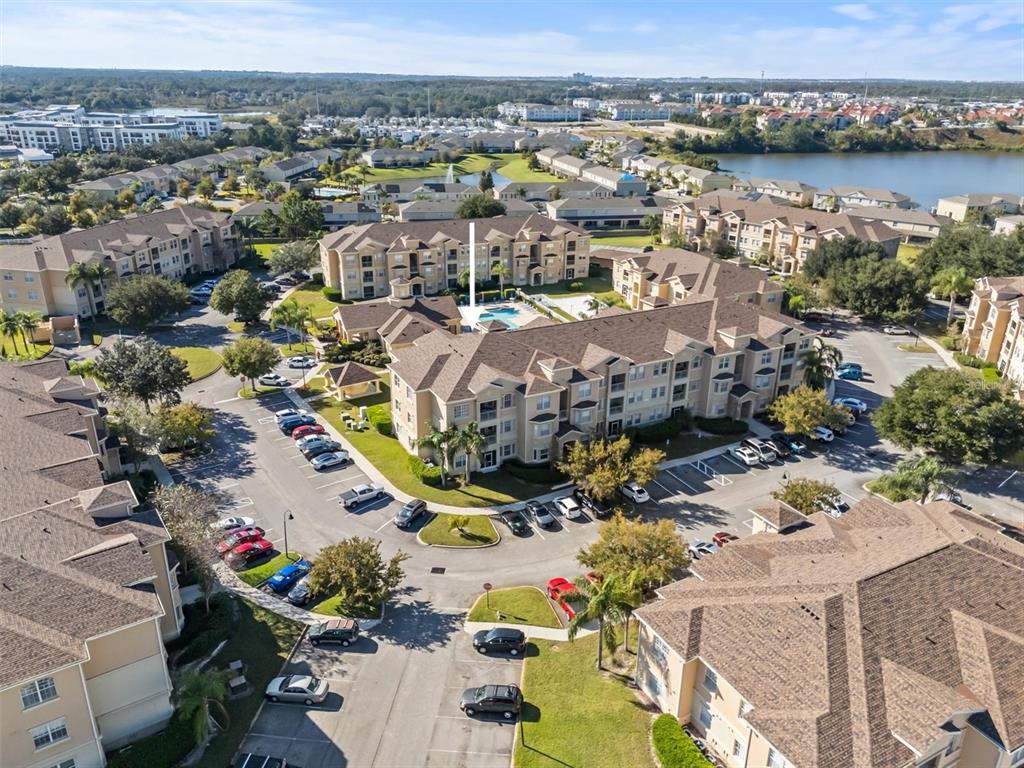 An aerial view shows a multi-story apartment complex with a central swimming pool and parking — 301 TERRACE RIDGE CIRCLE UNIT 301, DAVENPORT, FL
