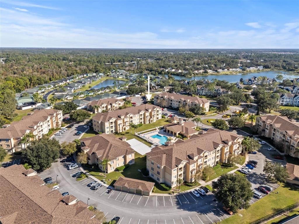 An aerial view shows a multi-story apartment complex with a central swimming pool and parking — 301 TERRACE RIDGE CIRCLE UNIT 301, DAVENPORT, FL