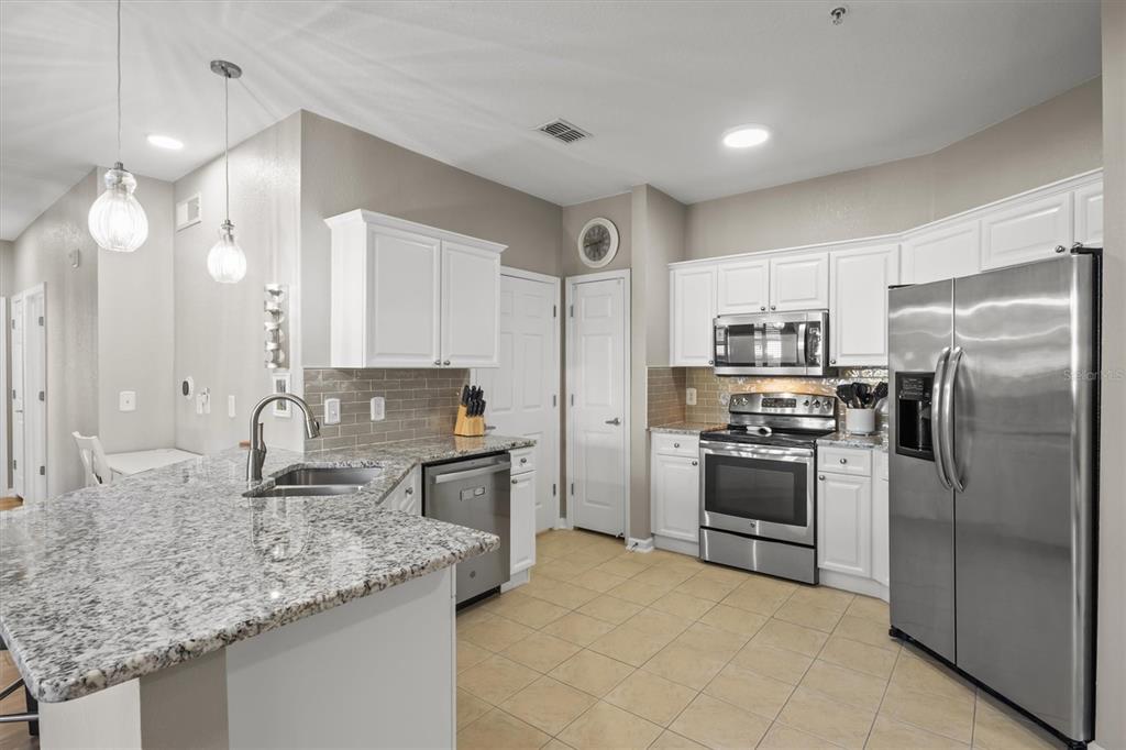 A kitchen features white cabinets, granite countertops, stainless steel appliances, and a tile floor — 301 TERRACE RIDGE CIRCLE UNIT 301, DAVENPORT, FL