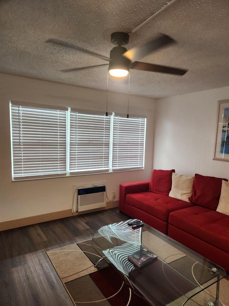 A living room features a red sofa, a glass coffee table, and a ceiling fan — 102 E Westbury # 102, Deerfield Beach FL 33442, DEERFIELD BEACH, FL