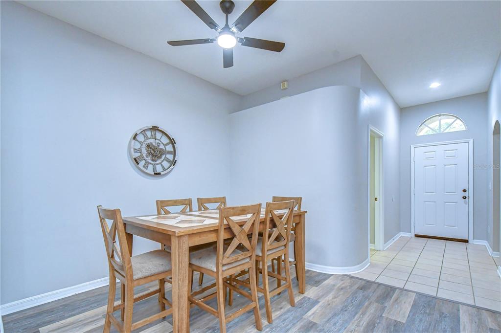 A dining area features a wooden table, four chairs, a wall clock, and a ceiling fan — 11117 RODEO LANE, RIVERVIEW, FL