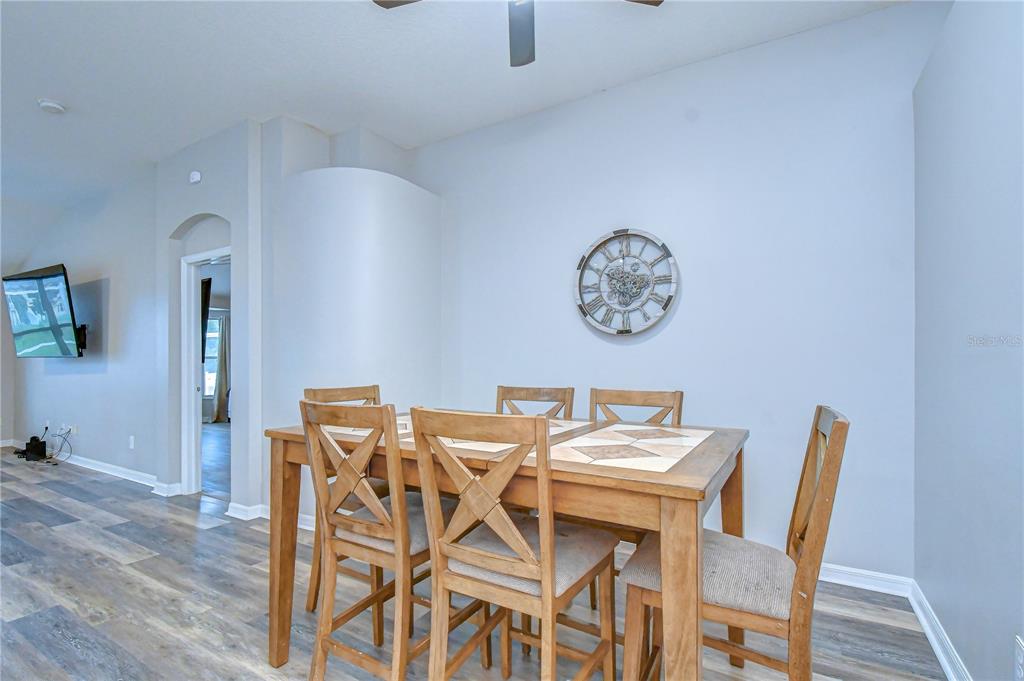 A dining area features a wooden table with chairs, light gray walls, and wood-look flooring — 11117 RODEO LANE, RIVERVIEW, FL