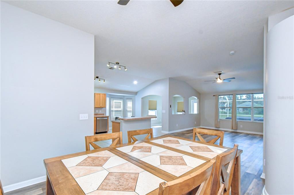 A dining room with a tiled table overlooks an open-concept kitchen and living area — 11117 RODEO LANE, RIVERVIEW, FL
