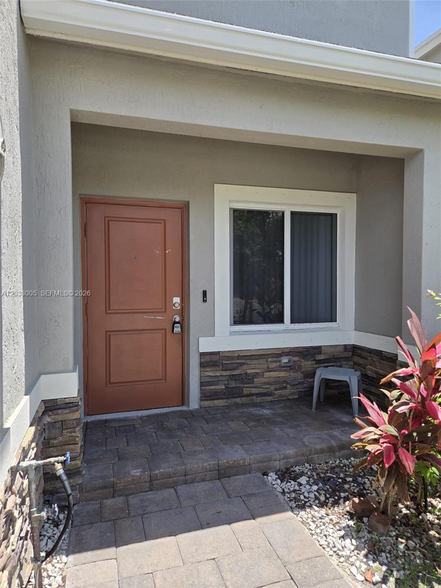 A brown front door and a window are set into a stone-accented exterior wall — 862 SE 17th St # 862, Homestead FL 33034, HOMESTEAD, FL
