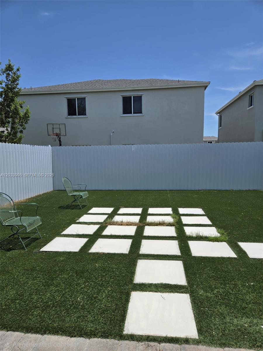A backyard features artificial turf, square concrete pavers, and two metal chairs against a fence — 862 SE 17th St # 862, Homestead FL 33034, HOMESTEAD, FL