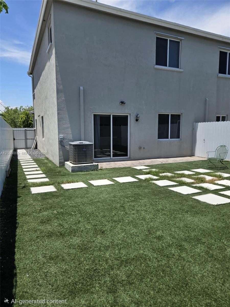 A two-story house exterior features a grassy backyard with stone pavers and an air conditioner — 862 SE 17th St # 862, Homestead FL 33034, HOMESTEAD, FL
