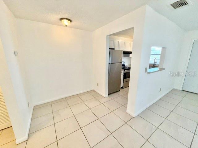A dining area with tiled floors leads into a kitchen featuring stainless steel appliances — 501 W OHIO AVENUE UNIT 22, DELAND, FL