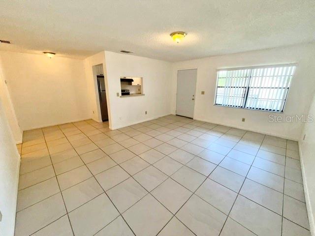 An open-concept living area features light-colored floor tiles, a white ceiling, and a kitchen pass-through — 501 W OHIO AVENUE UNIT 22, DELAND, FL