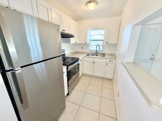 A kitchen features white cabinets, stainless steel appliances, and light-colored floor tiles — 501 W OHIO AVENUE UNIT 22, DELAND, FL