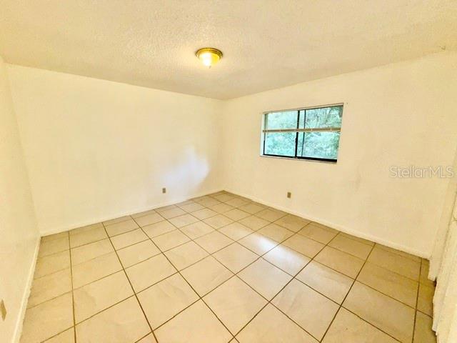 An empty bedroom with white walls, a single window, and light-colored tile flooring — 501 W OHIO AVENUE UNIT 22, DELAND, FL
