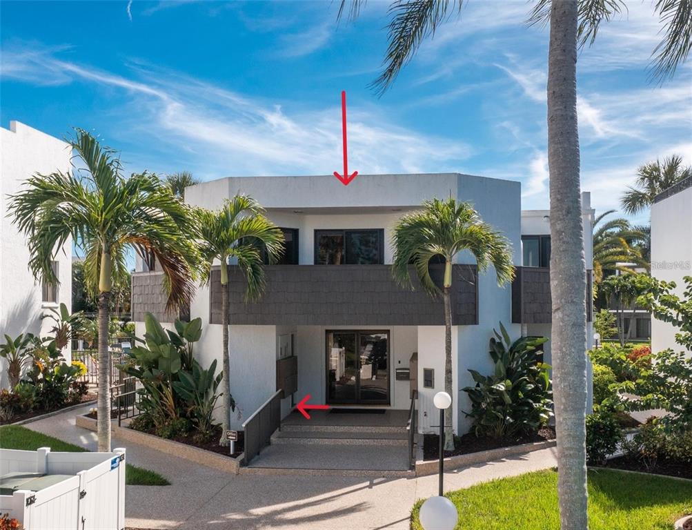 An exterior view of a two-story building with a balcony and a central entrance — 2955 N BEACH ROAD UNIT E122, ENGLEWOOD, FL