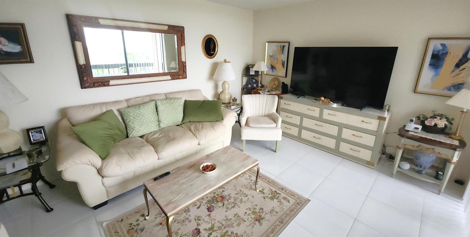 A living room features a beige sofa, a television on a dresser, and tile flooring — 2455 Lindell Boulevard # 3511, Delray Beach FL 33444, DELRAY BEACH, FL
