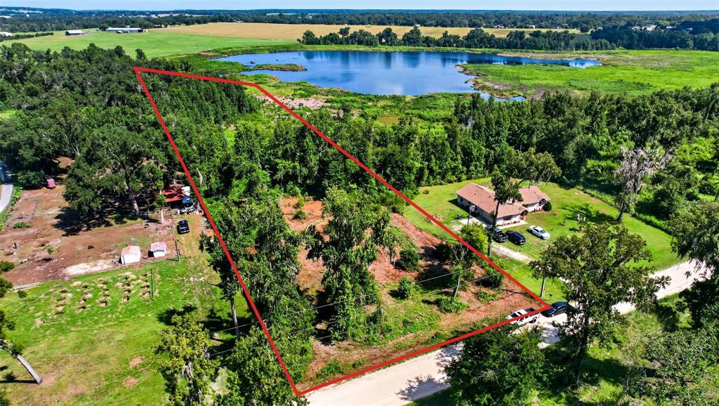 An aerial view shows a large, wooded lot outlined in red next to a lake — 0 SUMNER LAKE ROAD, DADE CITY, FL