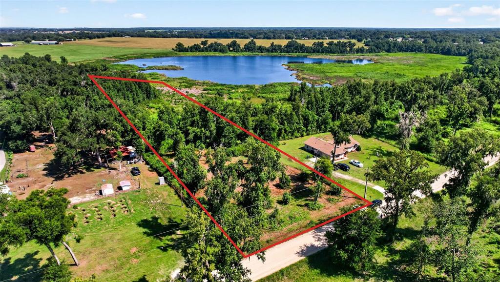 An aerial view shows a wooded lot outlined in red next to a lake — 0 SUMNER LAKE ROAD, DADE CITY, FL