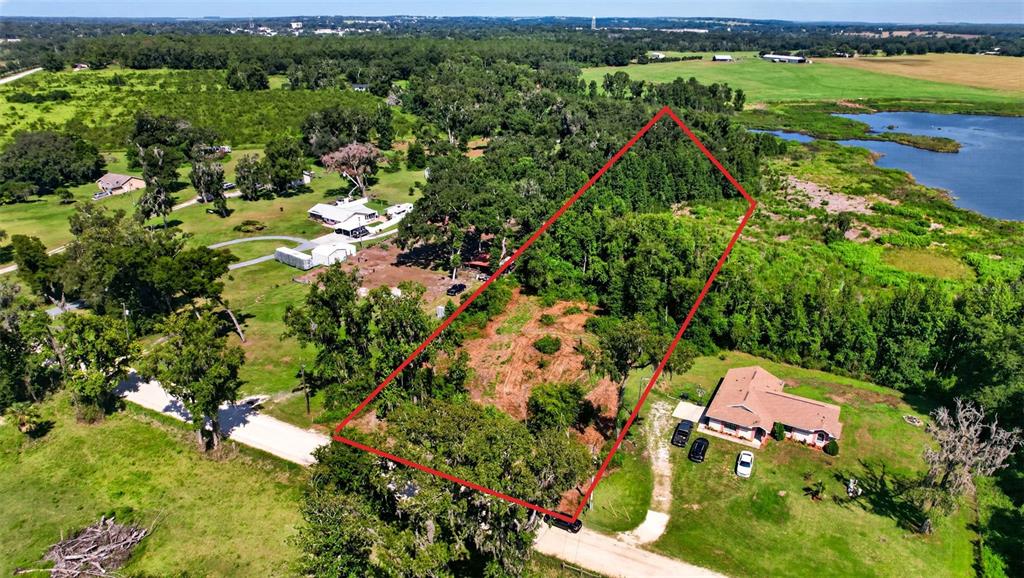 An aerial view shows a wooded lot outlined in red next to a residential house — 0 SUMNER LAKE ROAD, DADE CITY, FL