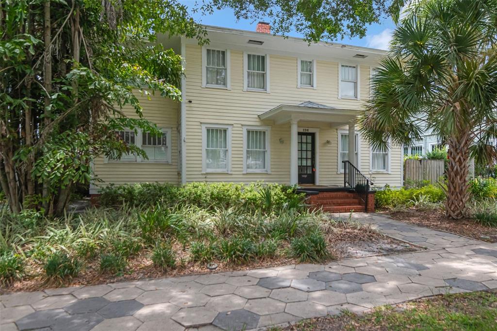 A two-story, yellow-sided house with a front porch and a hexagonal paver walkway — 126 8TH AVENUE NE, ST PETERSBURG, FL