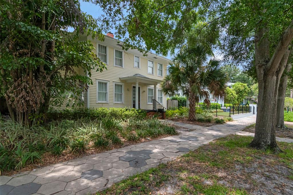 A two-story yellow house with a front porch sits behind a hexagonal paver sidewalk — 126 8TH AVENUE NE, ST PETERSBURG, FL