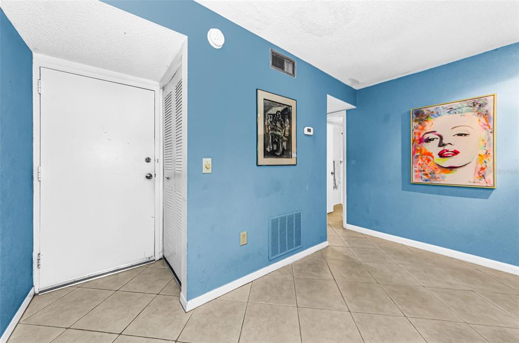 An entryway with blue walls, tile flooring, a white door, and a Marilyn Monroe painting — 11436 2ND STREET N UNIT 1, ST PETERSBURG, FL