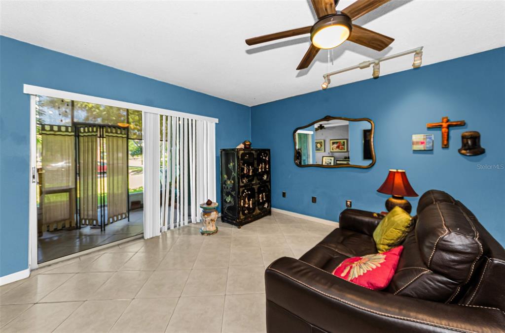 A living room features blue walls, tile flooring, a leather sofa, and a ceiling fan — 11436 2ND STREET N UNIT 1, ST PETERSBURG, FL