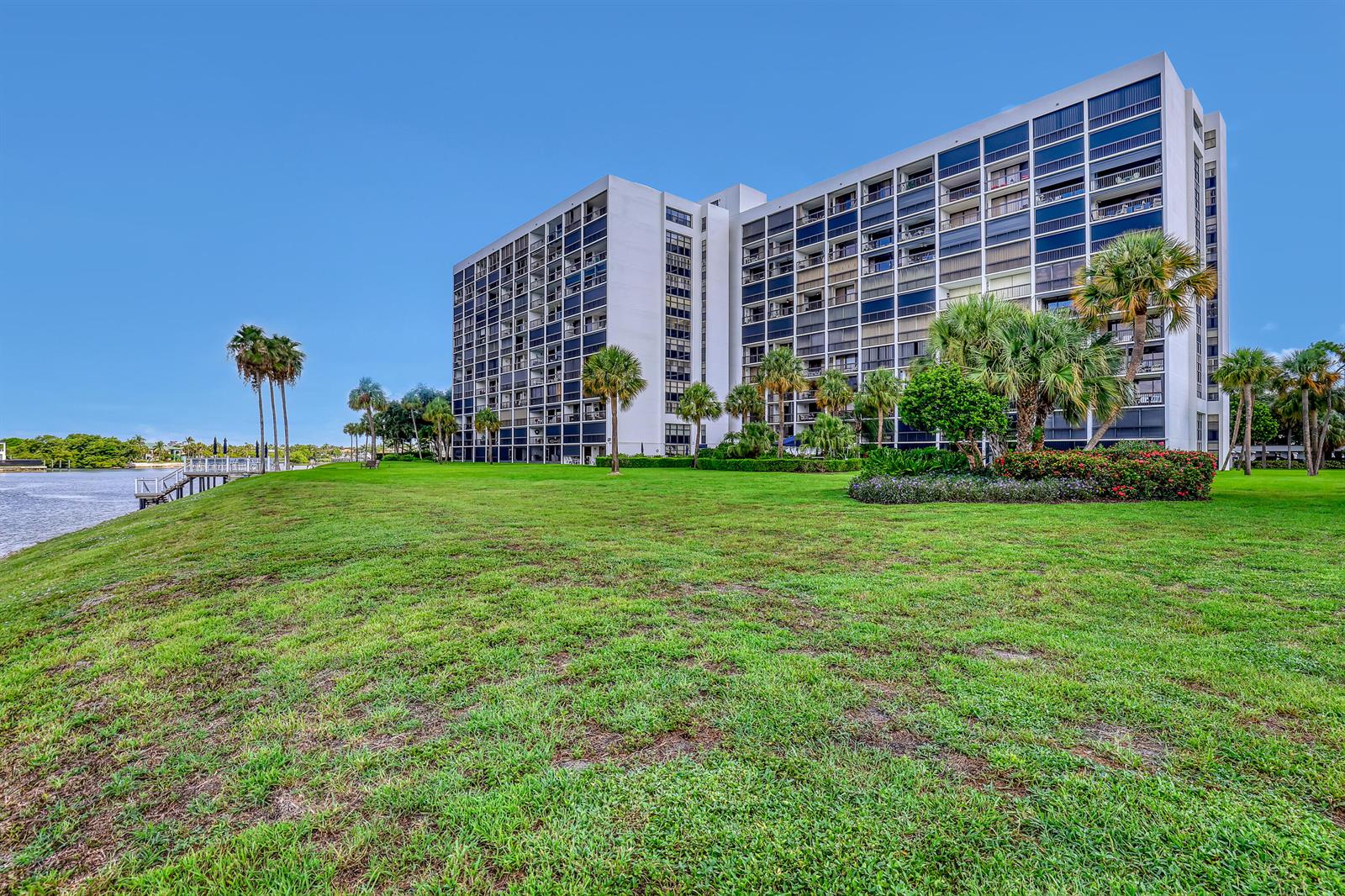 A large multi-story apartment building sits on a grassy lawn beside a body of water — 356 Golfview Road # 403, North Palm Beach FL 33408, NORTH PALM BEACH, FL