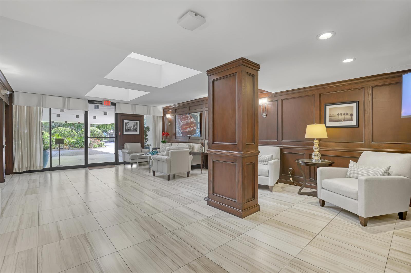 A lobby features wood-paneled walls, light-colored tile flooring, comfortable seating, and a large central pillar — 356 Golfview Road # 403, North Palm Beach FL 33408, NORTH PALM BEACH, FL