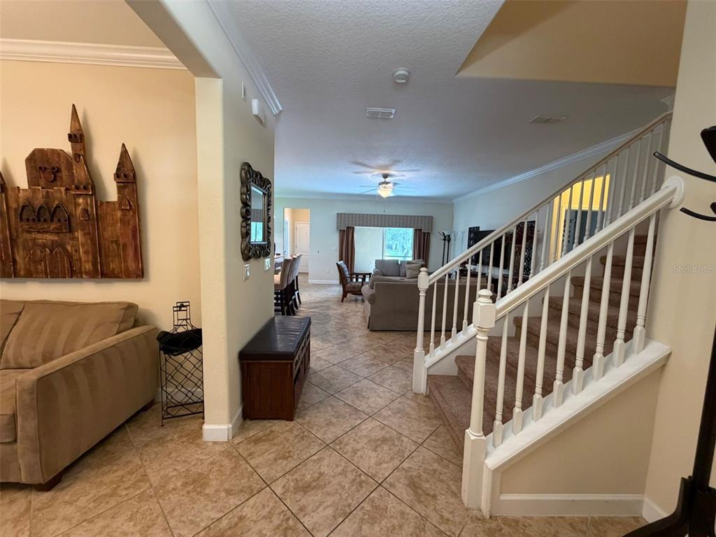 A foyer with tile flooring leads to a living area with a staircase on the right — 6206 POINT HANCOCK DRIVE, WINTER GARDEN, FL