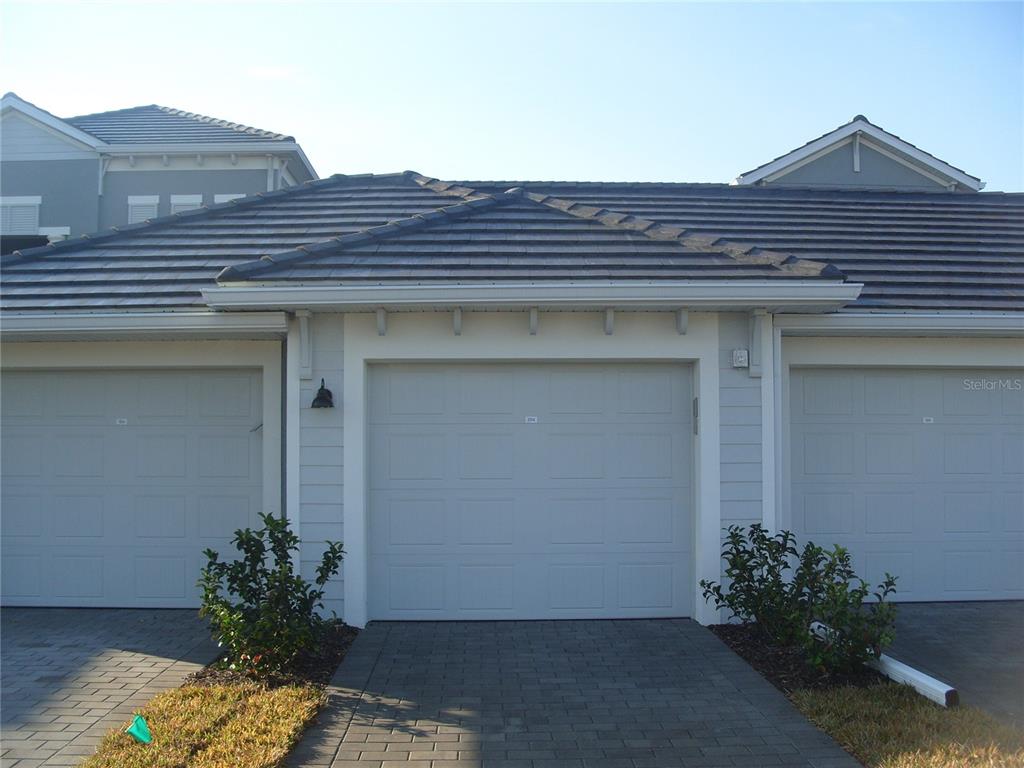 A view of a residential garage exterior with a paved driveway and gray siding — 17540 OPAL SAND DRIVE UNIT 204, VENICE, FL